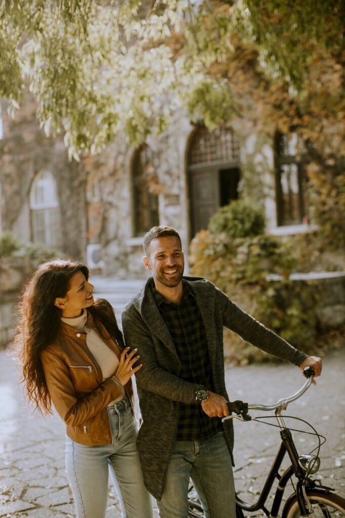 Young couple walking with bicycle in autumn park